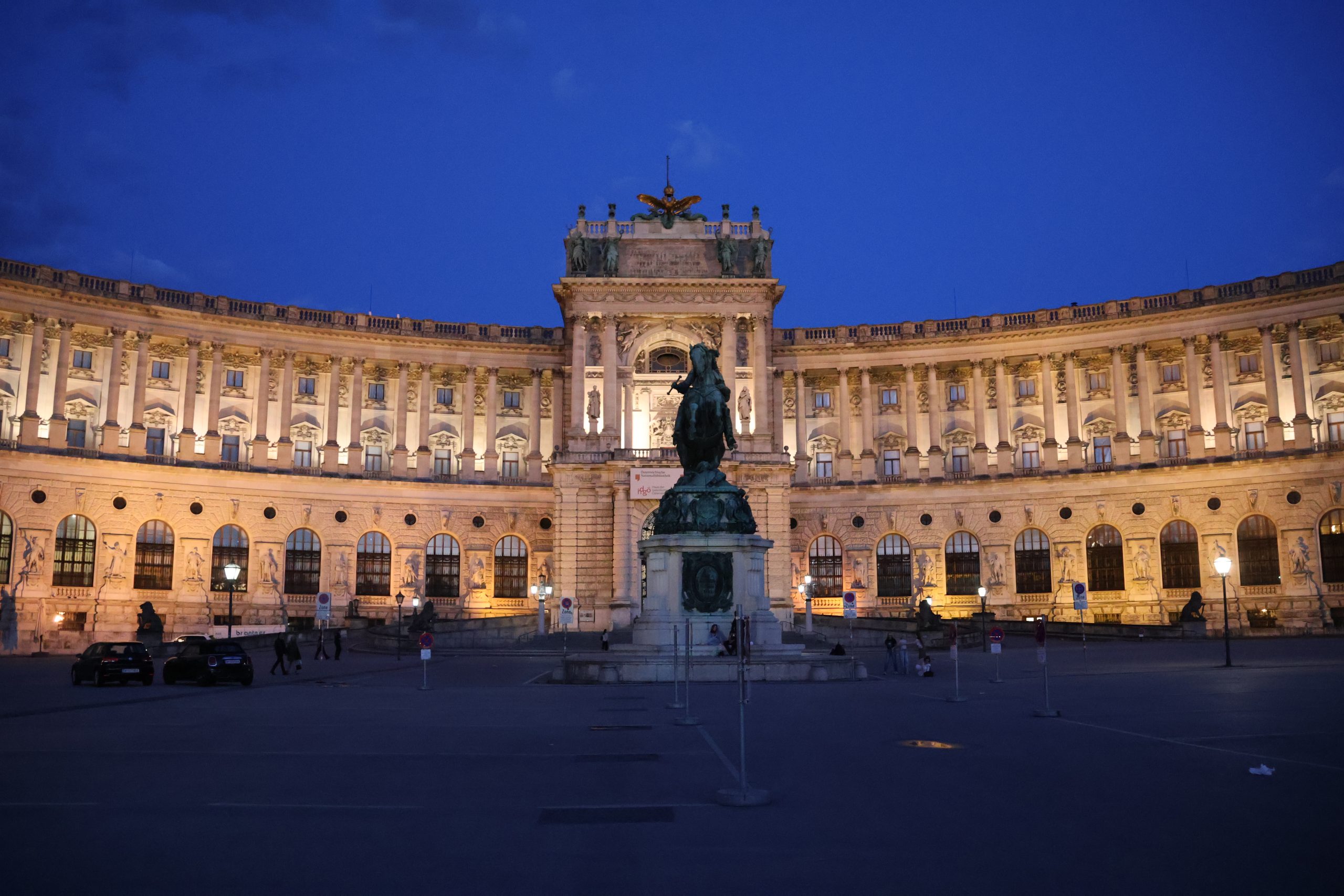 The Neue Burg building in Vienna beneath a sunset sky.