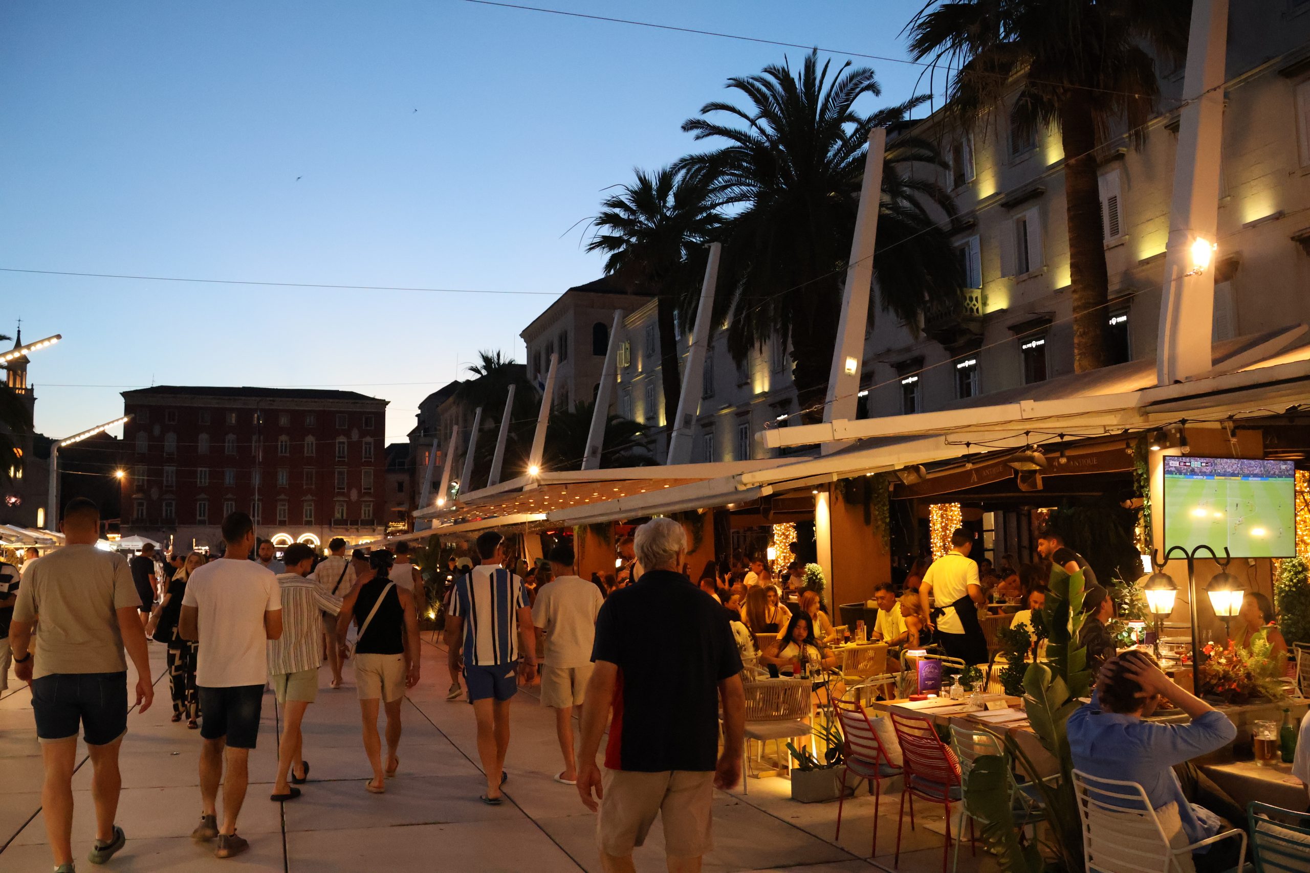 People walking along a street in Split at night.